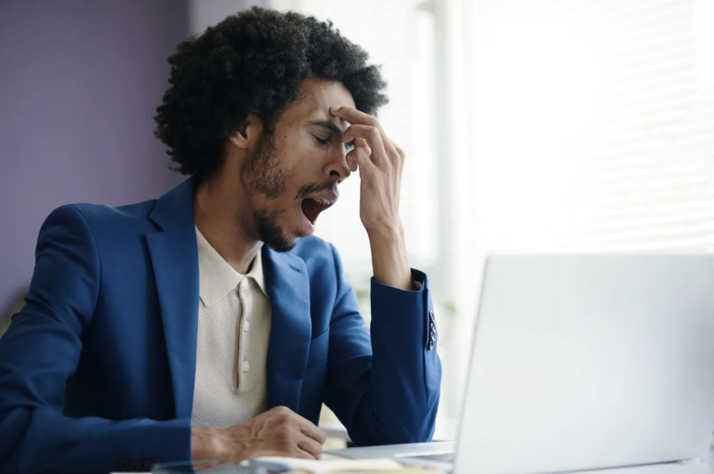 Man yawning at his computer