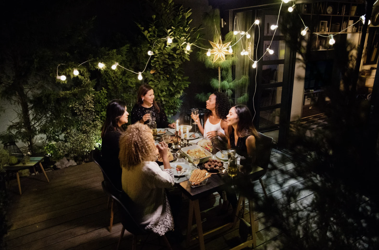 Friends eating dinner together outside under the dark sky