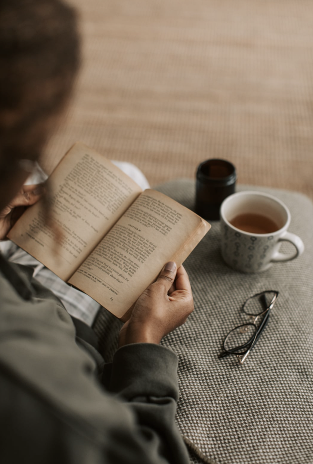 person reading a book with a cup of tea